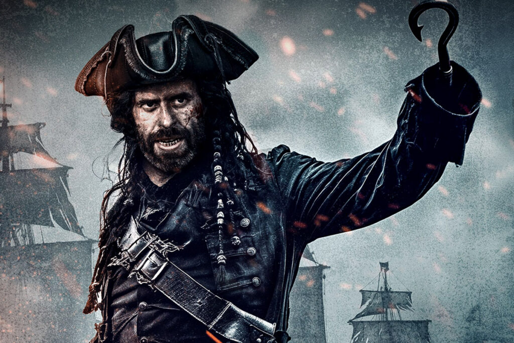 A photo of a pirate with a hook for a hand and a ship in the background.